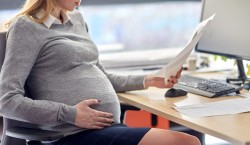 pregnant businesswoman reading papers at office